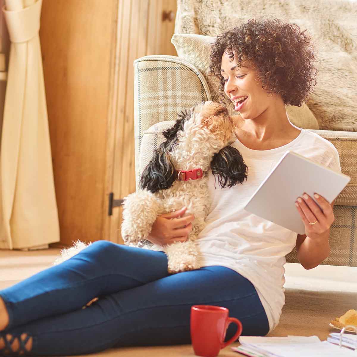 Woman cuddling with her dog while using her tablet, feeling confident and secure about her financial future