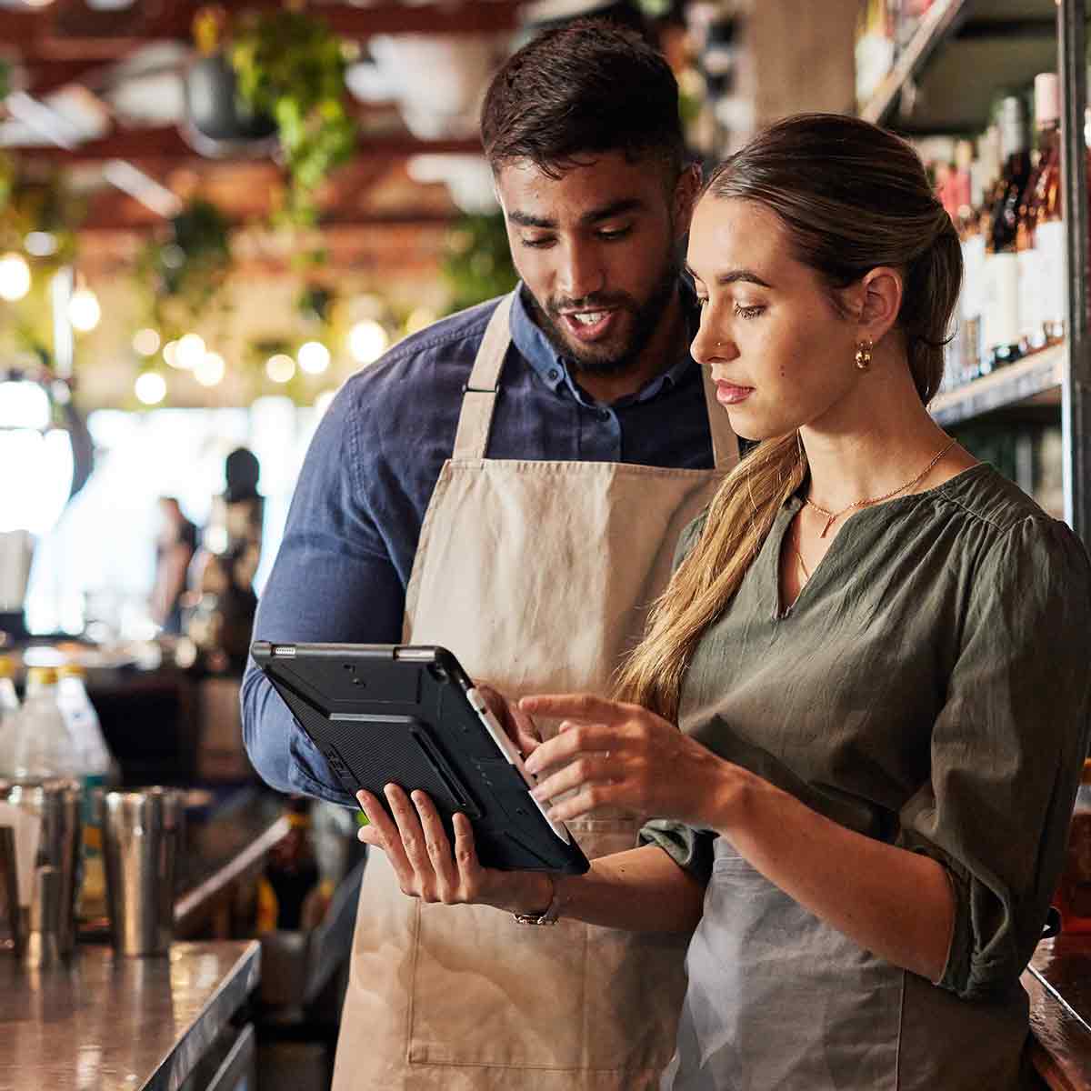 Small business owners using a tablet, strategizing on ways to grow their restaurant.