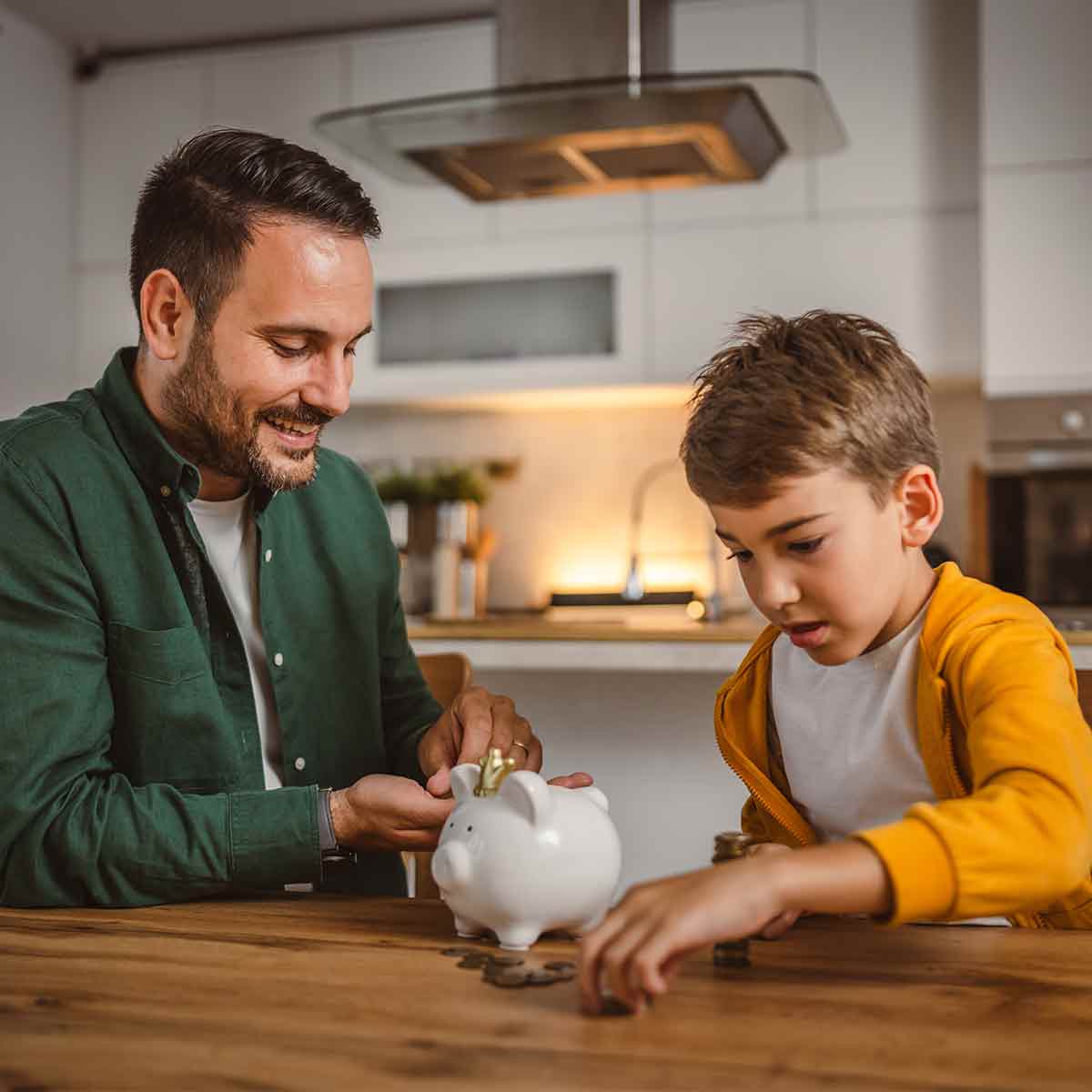 Father and son putting coins into a piggy bank, teaching savings habits