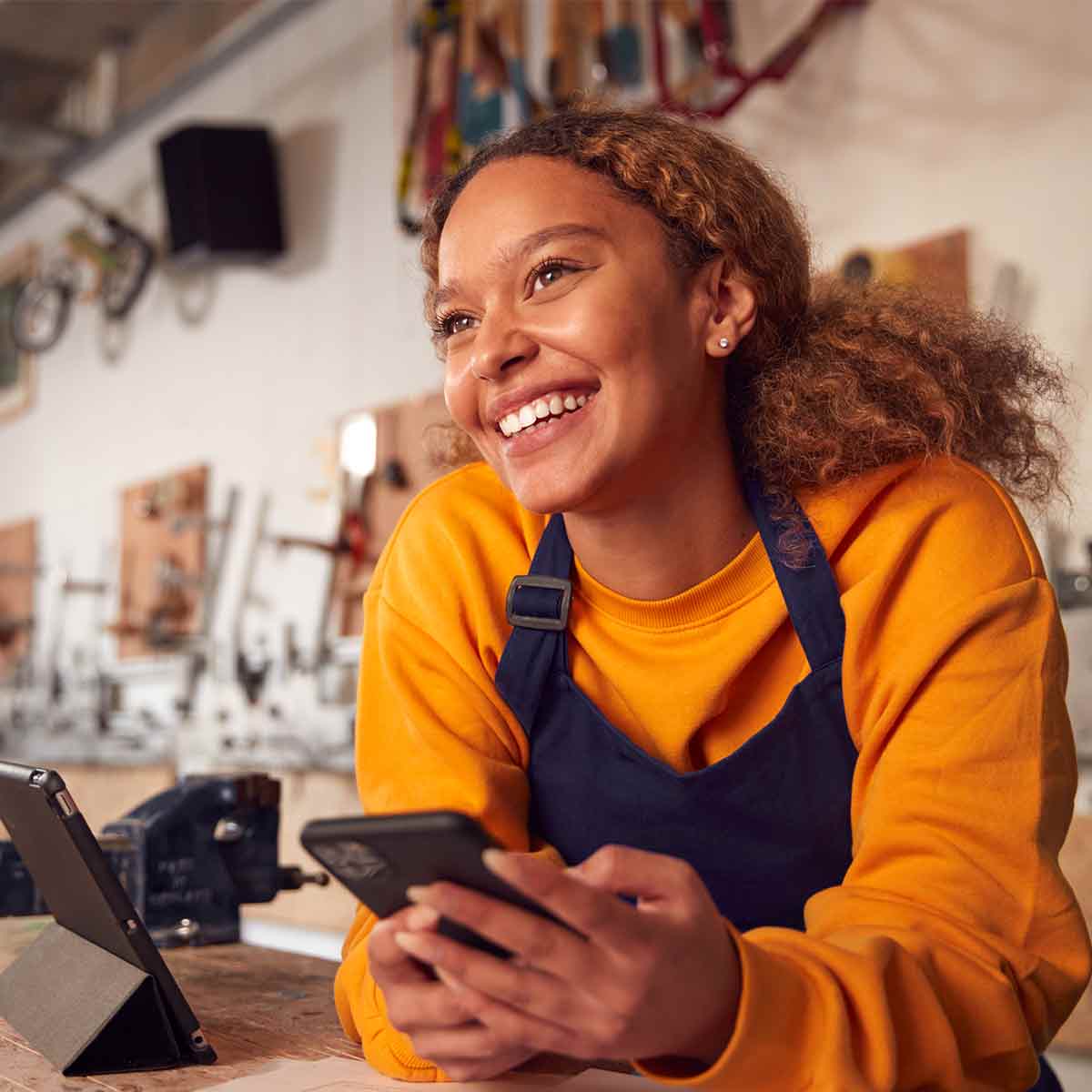 Female business owner in her workshop using her phone and tablet