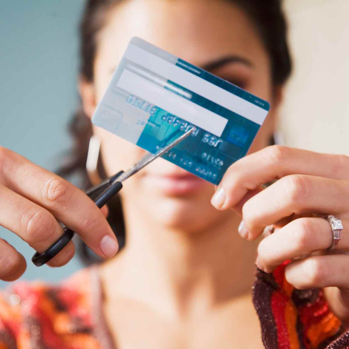 Woman cutting her credit card with scissors, demonstrating that you can pay off debt with the right strategies