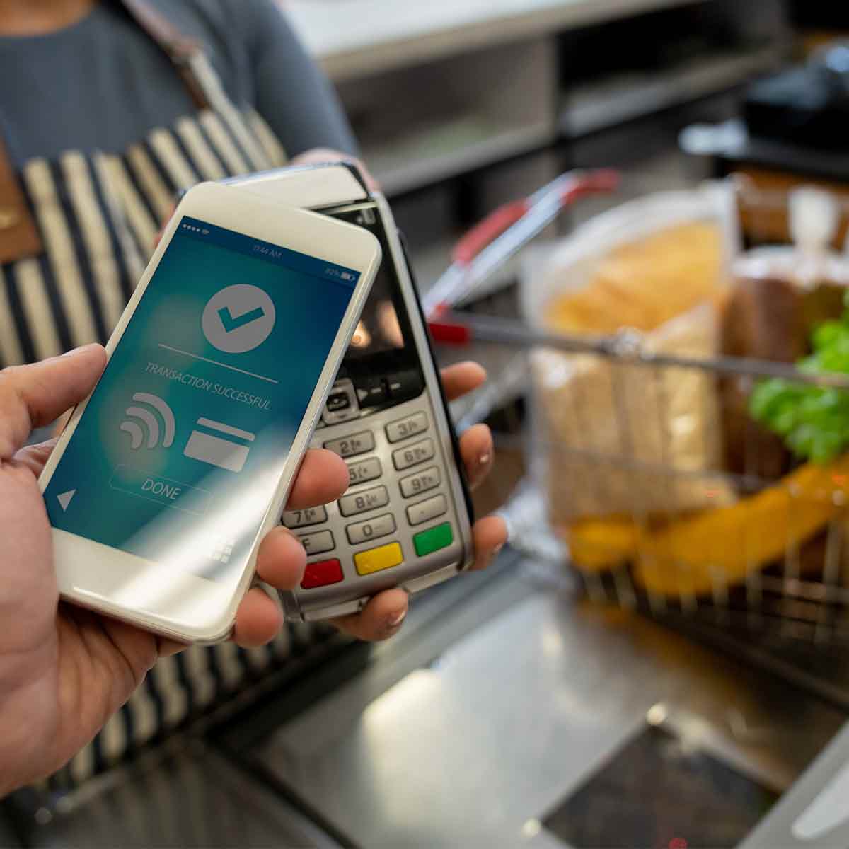 A person making a contactless payment at the supermarket, emphasizing the importance of smart budgeting
