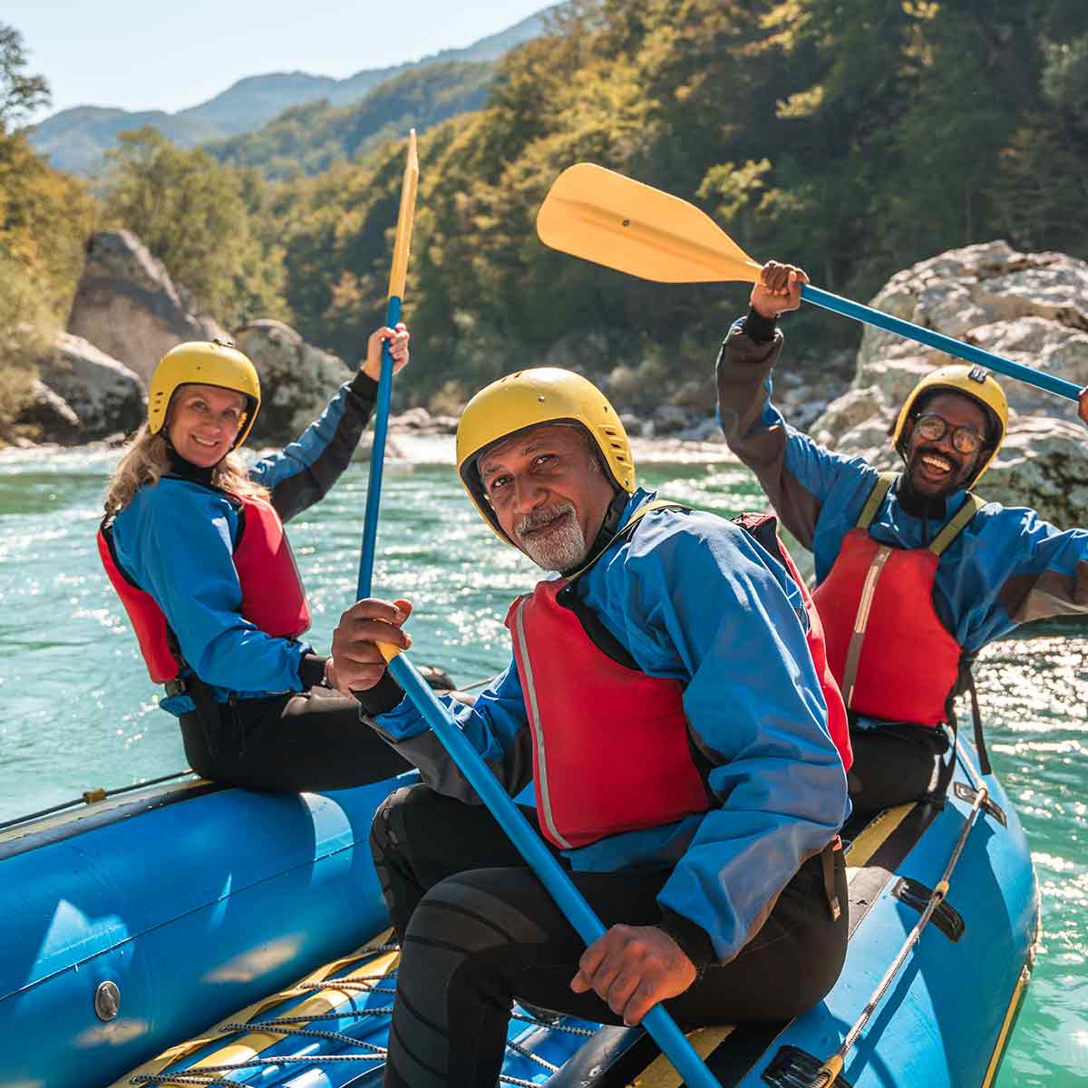 Three people kayaking on a mountain river, enjoying the freedom and adventure of retirement.