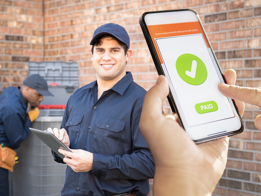 A man holds a smartphone displaying a check mark, confirming immediate payment for air conditioner repair services.