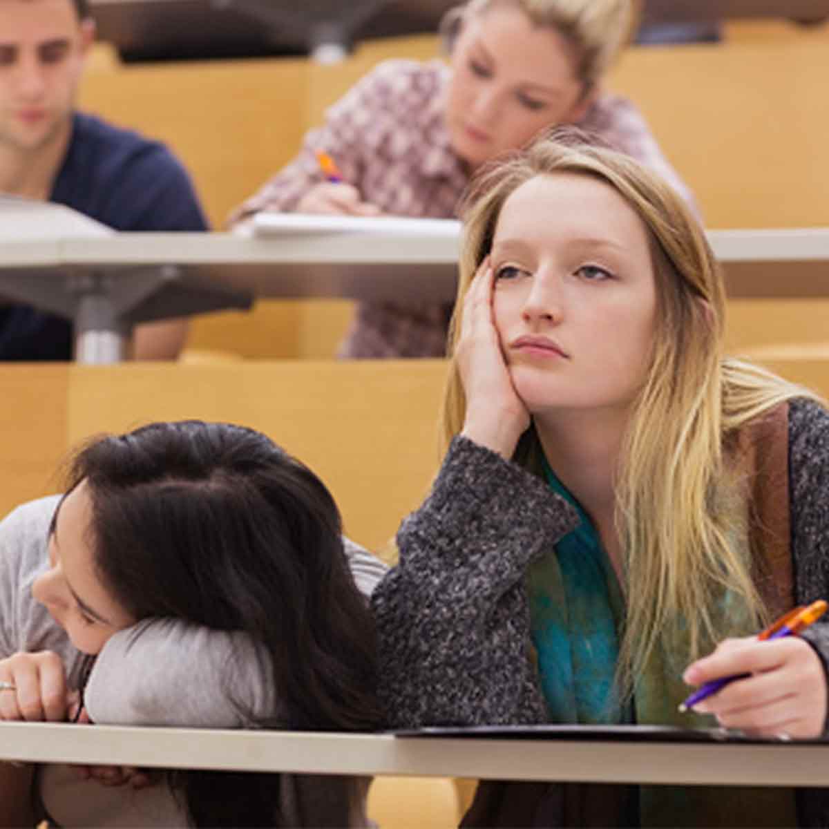 Two bored teenage girls in a classroom, showing why financial education needs to be engaging for teens