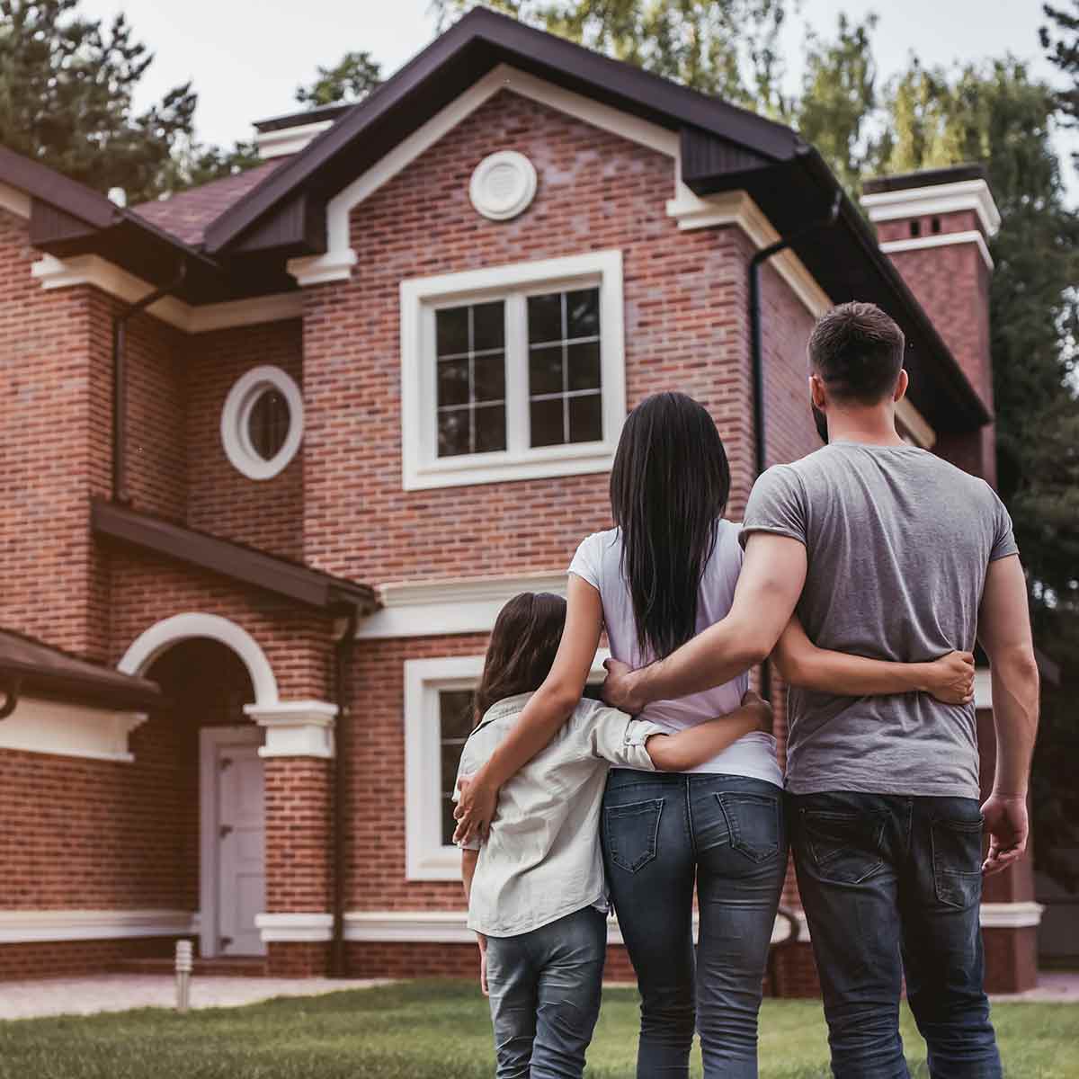 A family of three standing outside their new home, demonstrating how planning ahead helps getting approved for a mortgage