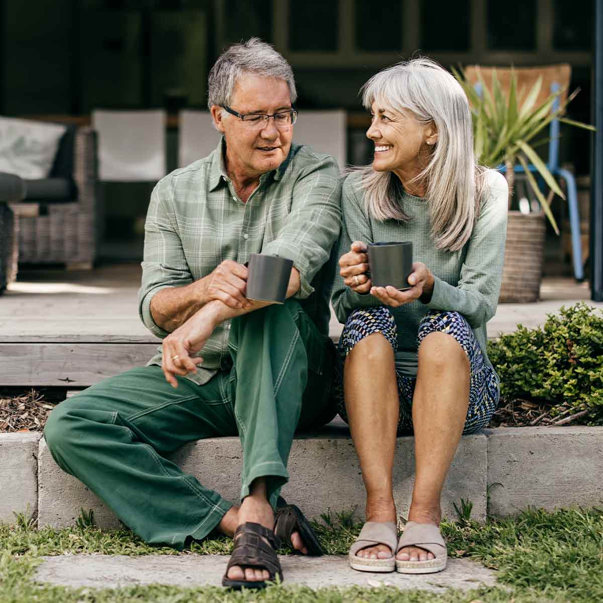 Retired couple sitting on a sunny porch, sipping coffee and enjoying each other’s company—living the fulfilling retirement they planned for.