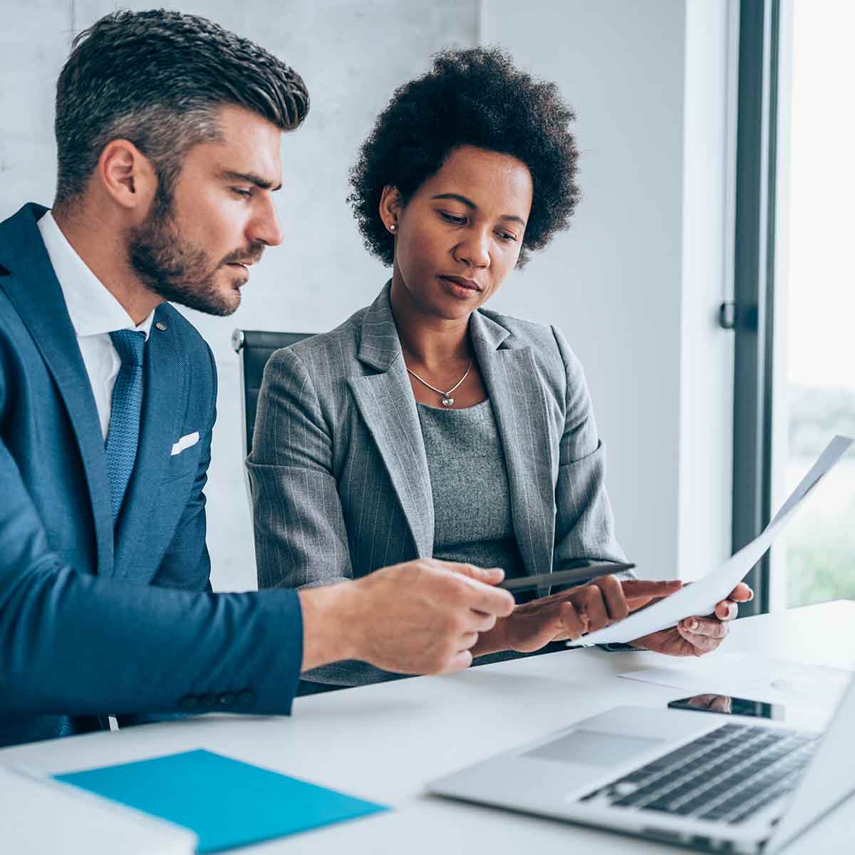 Two business people looking at economic reports, engaged in financial analysis and investment strategy