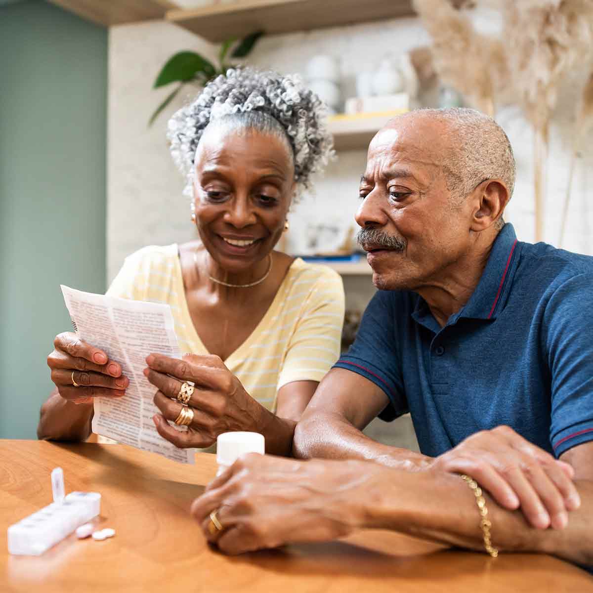 Older couple reviewing Medicare paperwork with medication on kitchen table