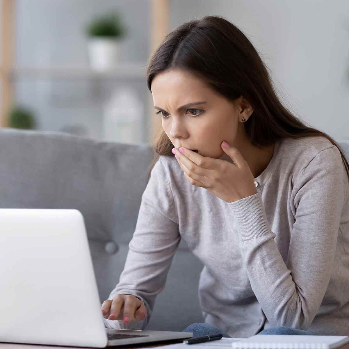 A teenage girl on her laptop, looking surprised and concerned about what she has found on the Internet