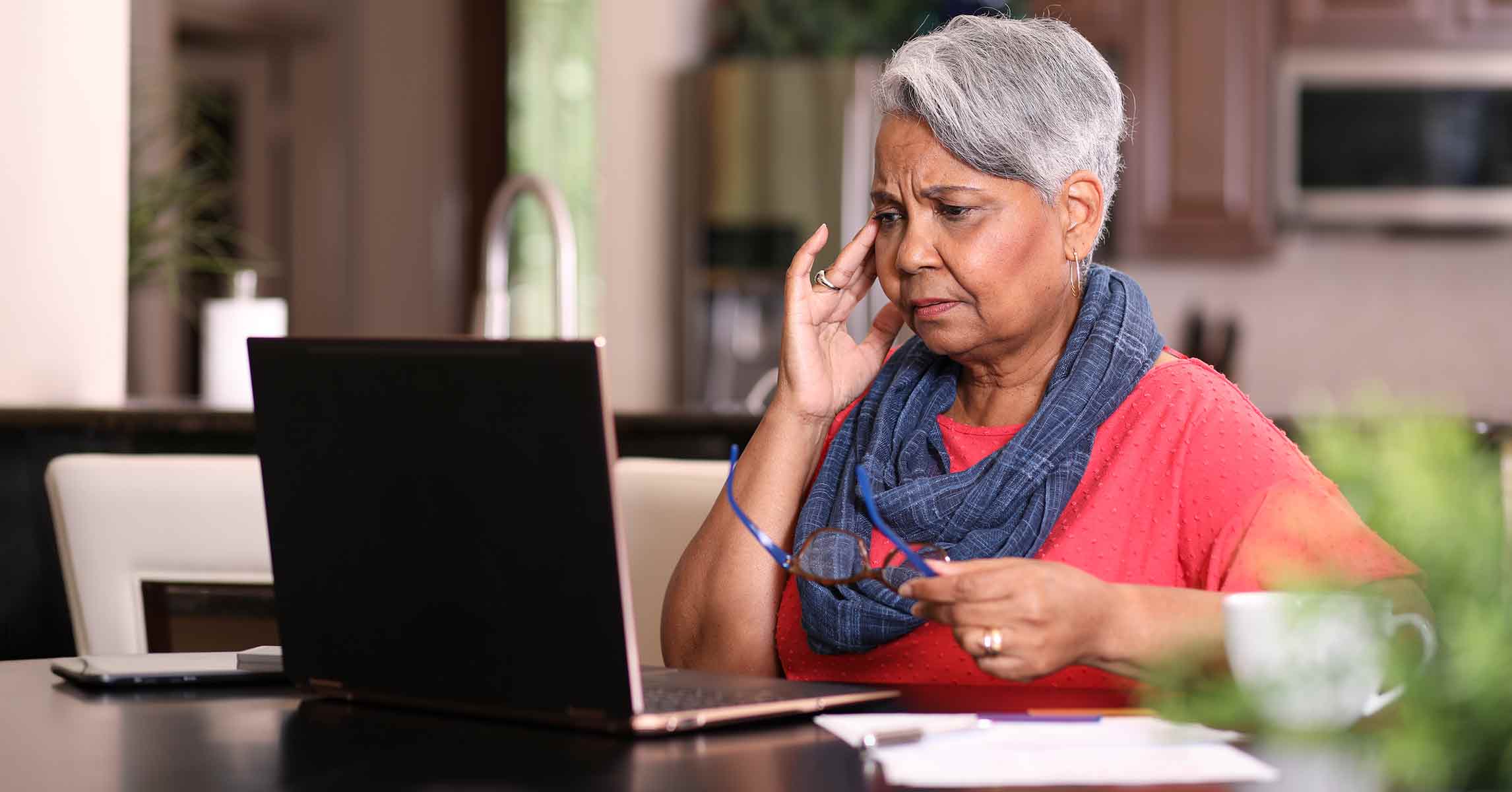 A dismayed older woman looks at her online banking statement and bill pay on her notebook