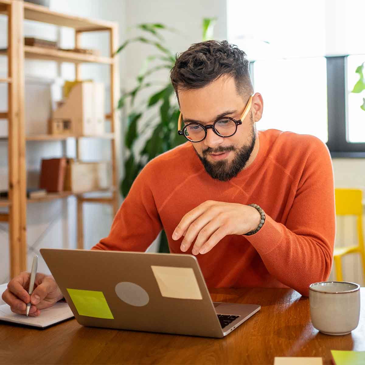 Man reviewing his finances on his laptop while taking notes