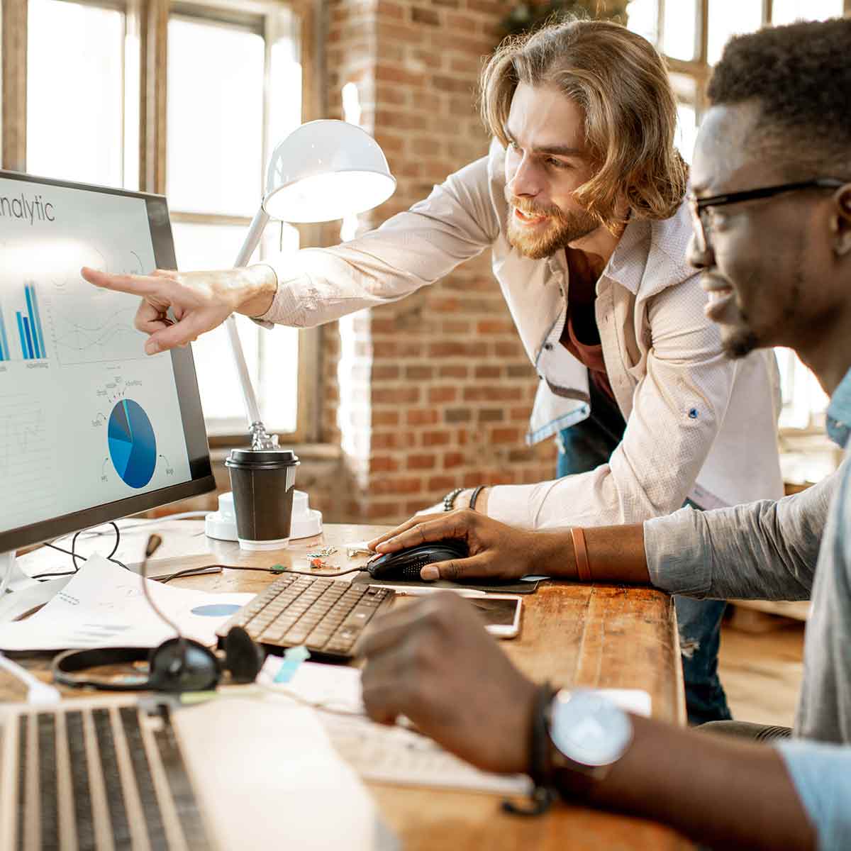 Two professionals looking at an economic chart on a computer screen, performing data analysis