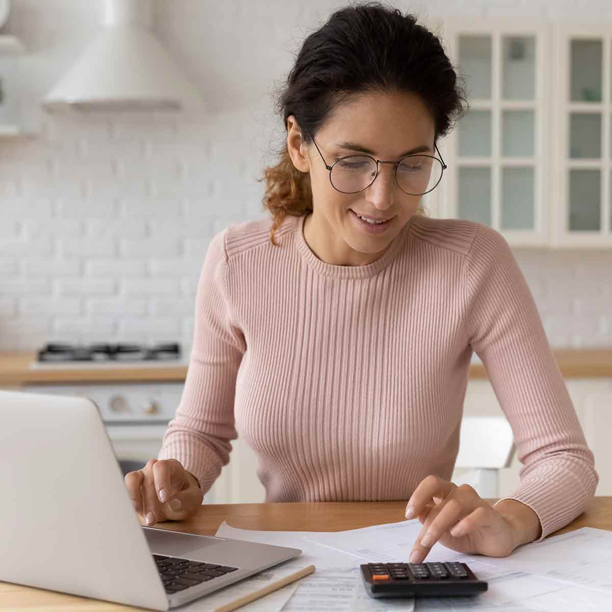 Woman using a laptop and calculator to calculate how interest affects her investments