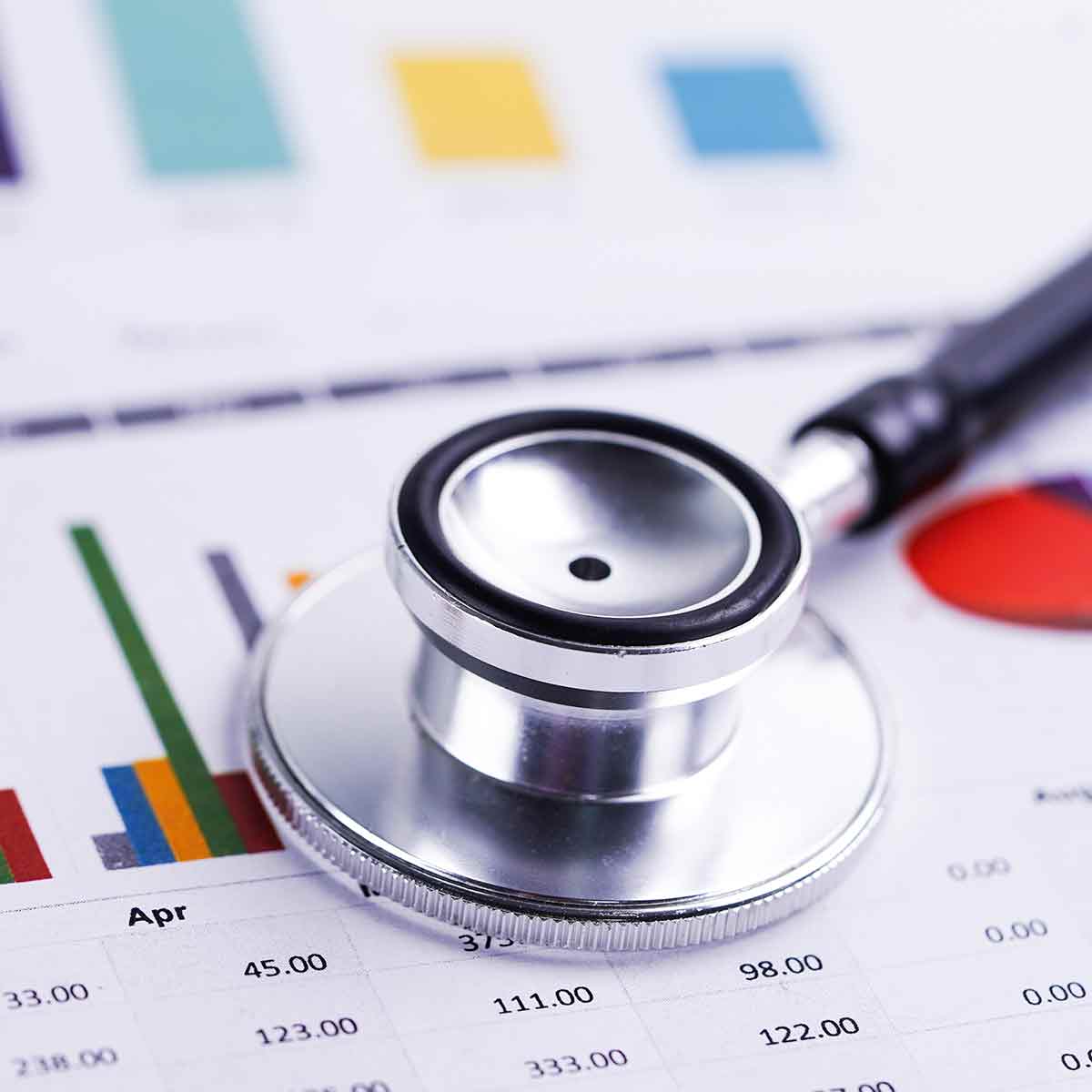 Stethoscope resting on year-end financial documents with charts and graphs