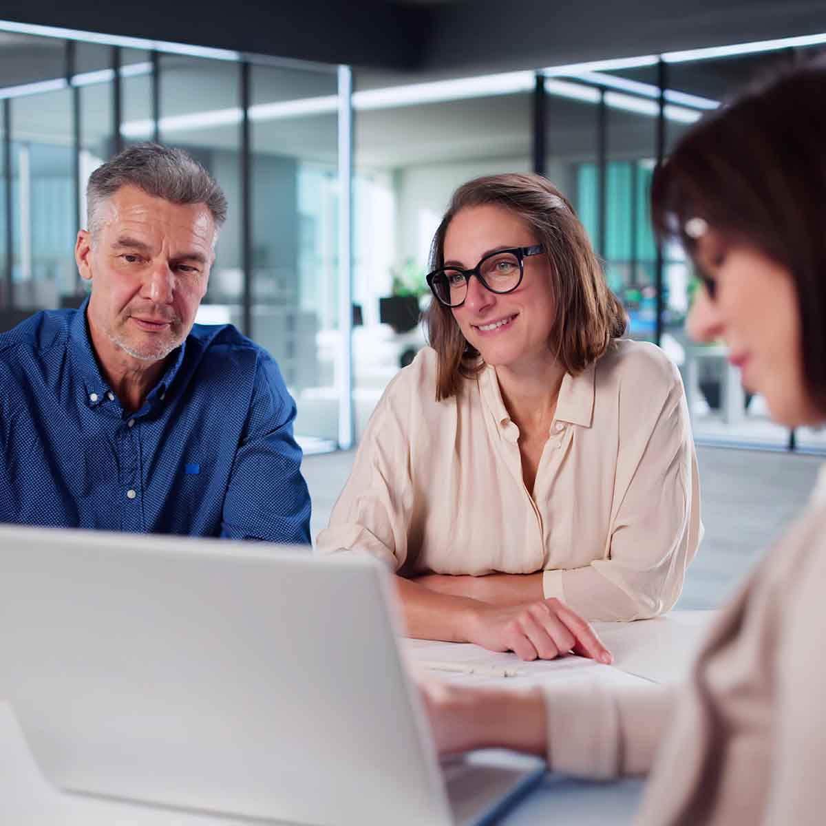 Financial advisor showing a laptop screen to a couple in her office during an investment discussion