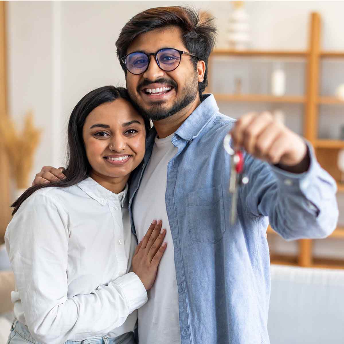 A happy couple moving into a new home and proudly holding up their keys