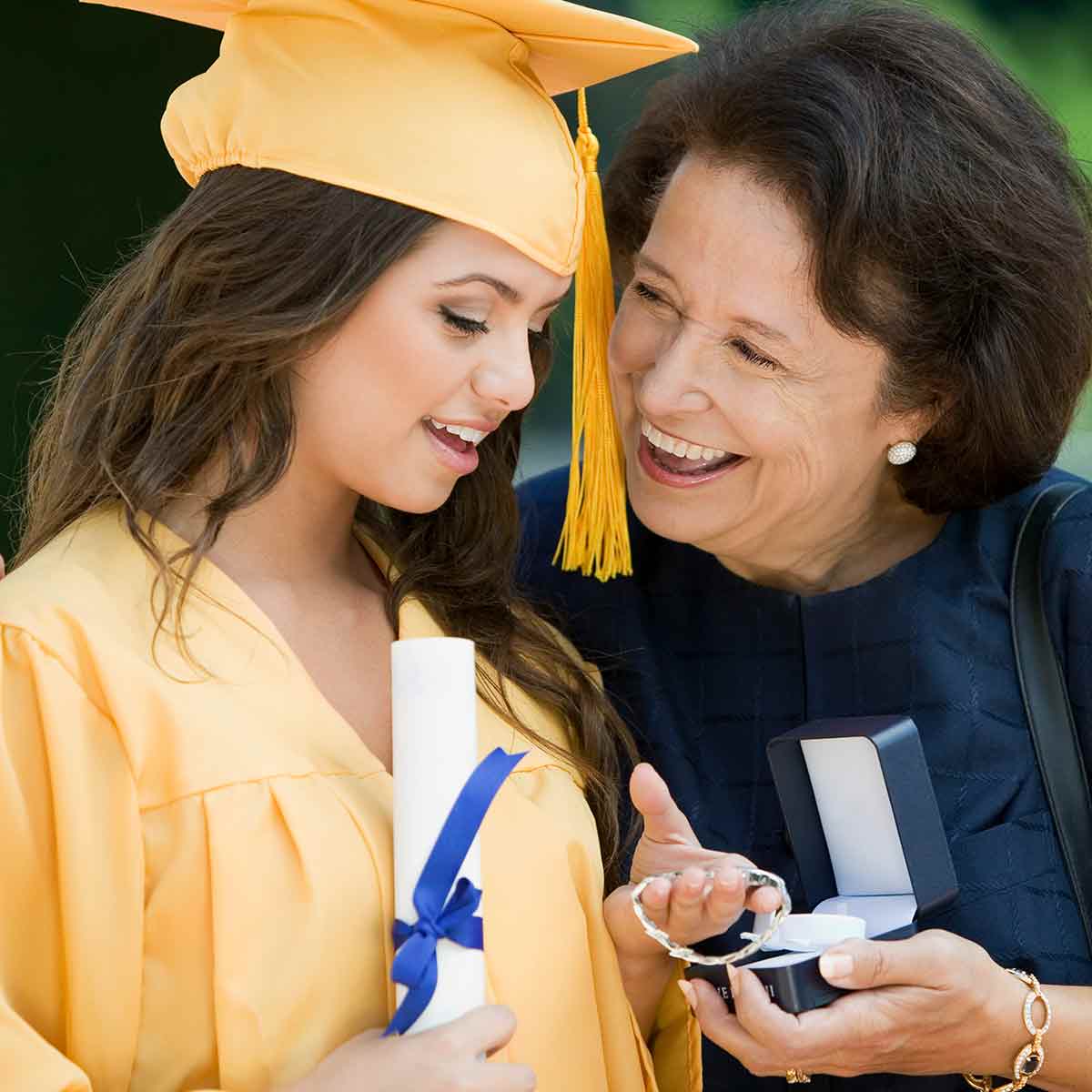 A mother gives her daughter a necklace as a gift at her graduation party.