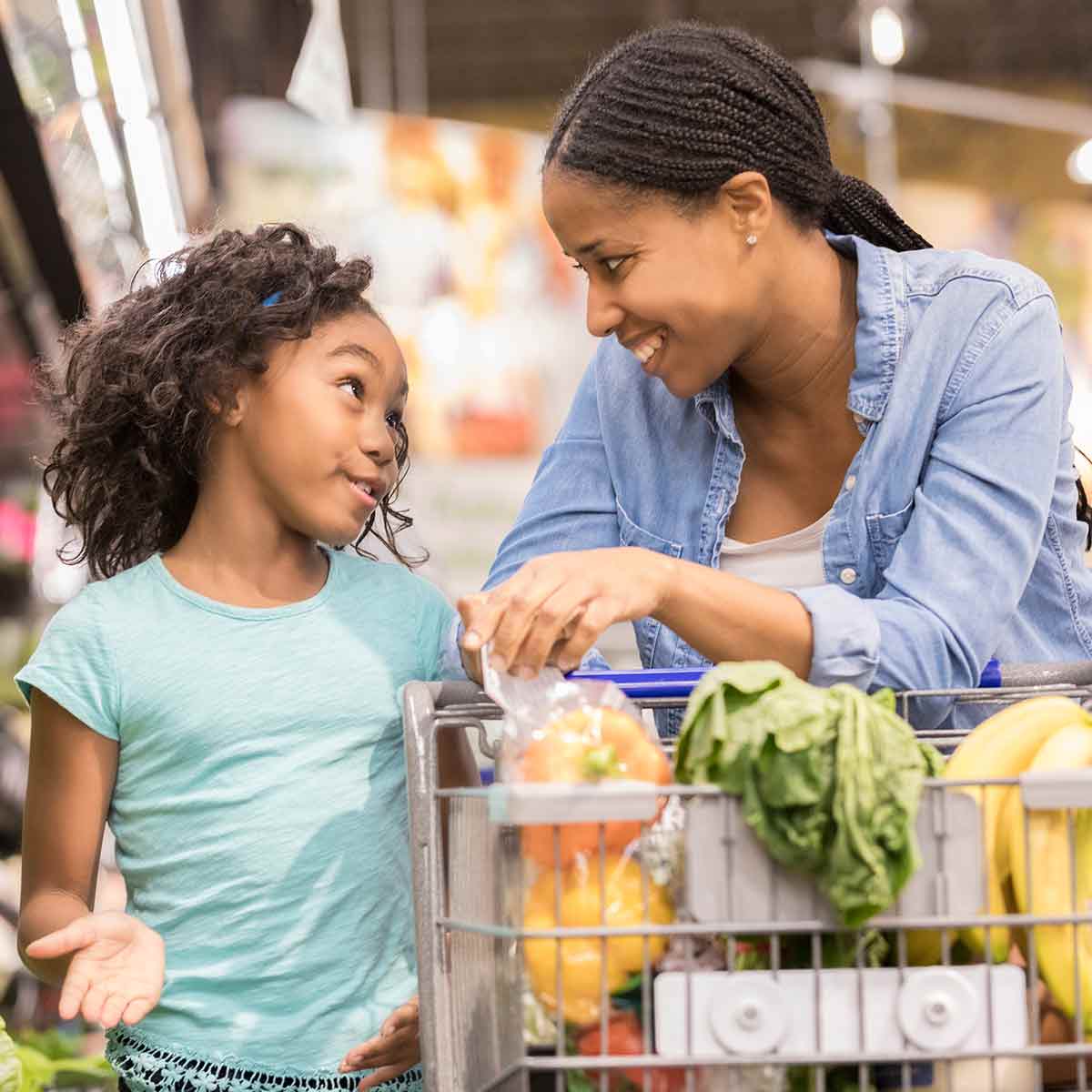 A mother and child grocery shopping together and talking about smart spending and everyday money choices