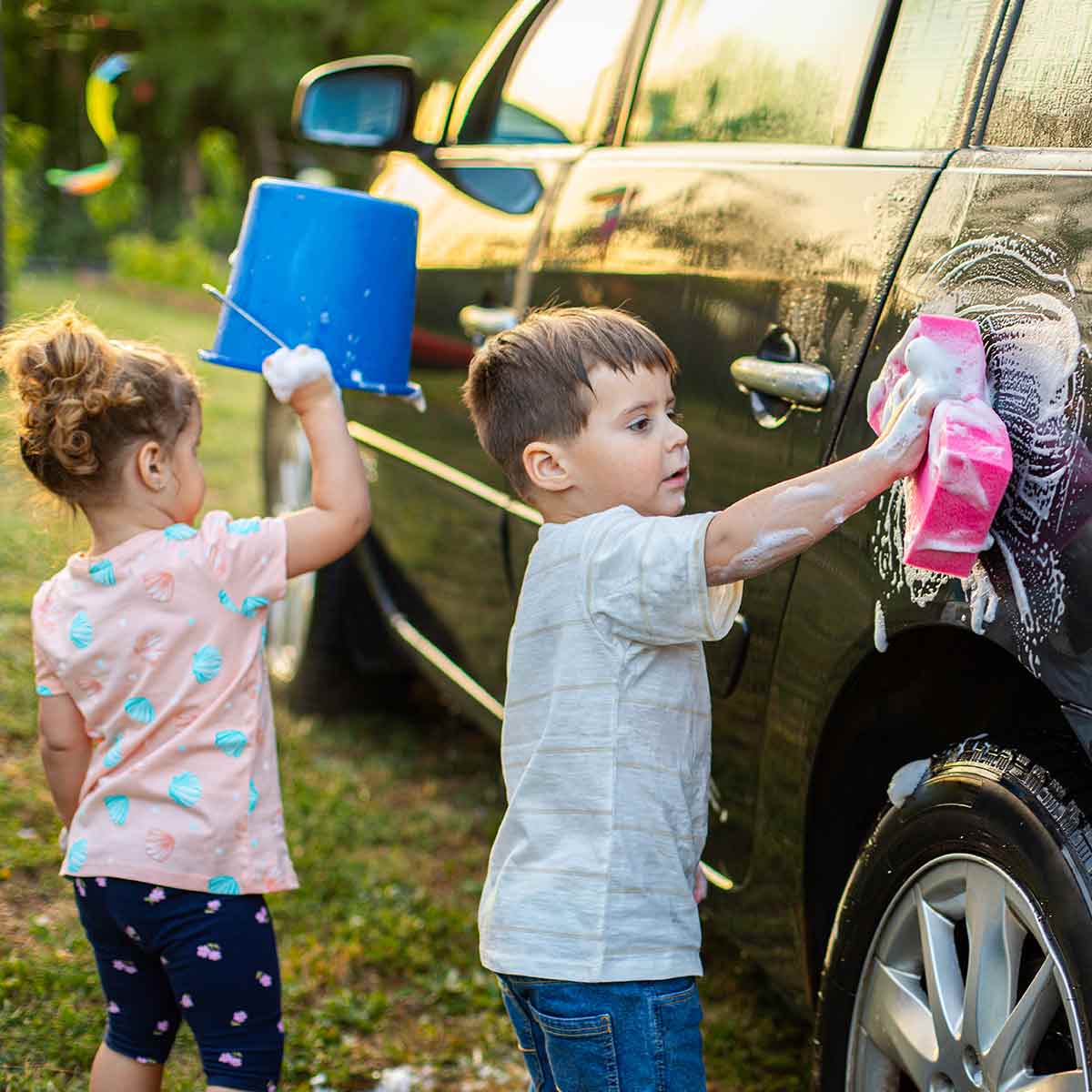 Two small children wash a card as part of their summer chores