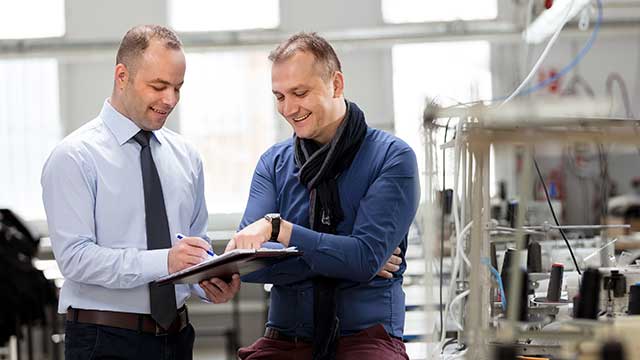 A banker meets with a manufacturing business owner on the shop floor