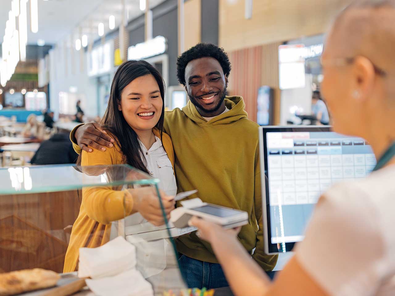 A couple paying for pizza with their 1st Source Bank debit card.