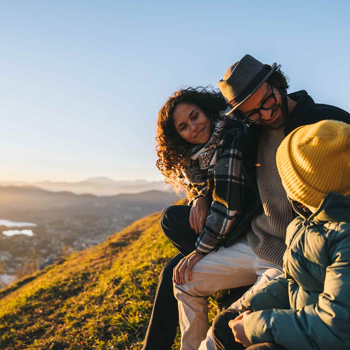 A family sits on a mountain at dusk, enjoying the vacation they have saved for