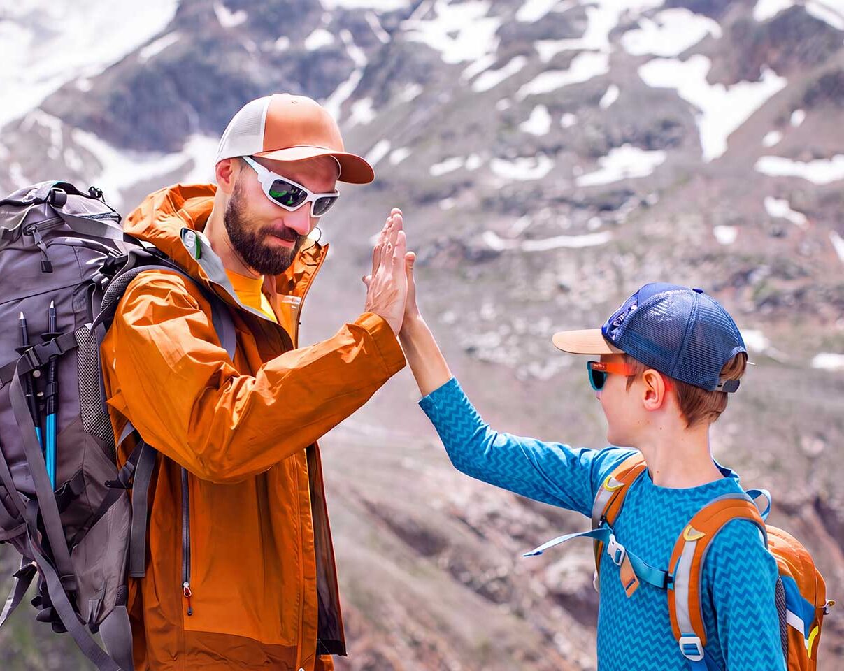A father and son share a high-five after hiking a mountain