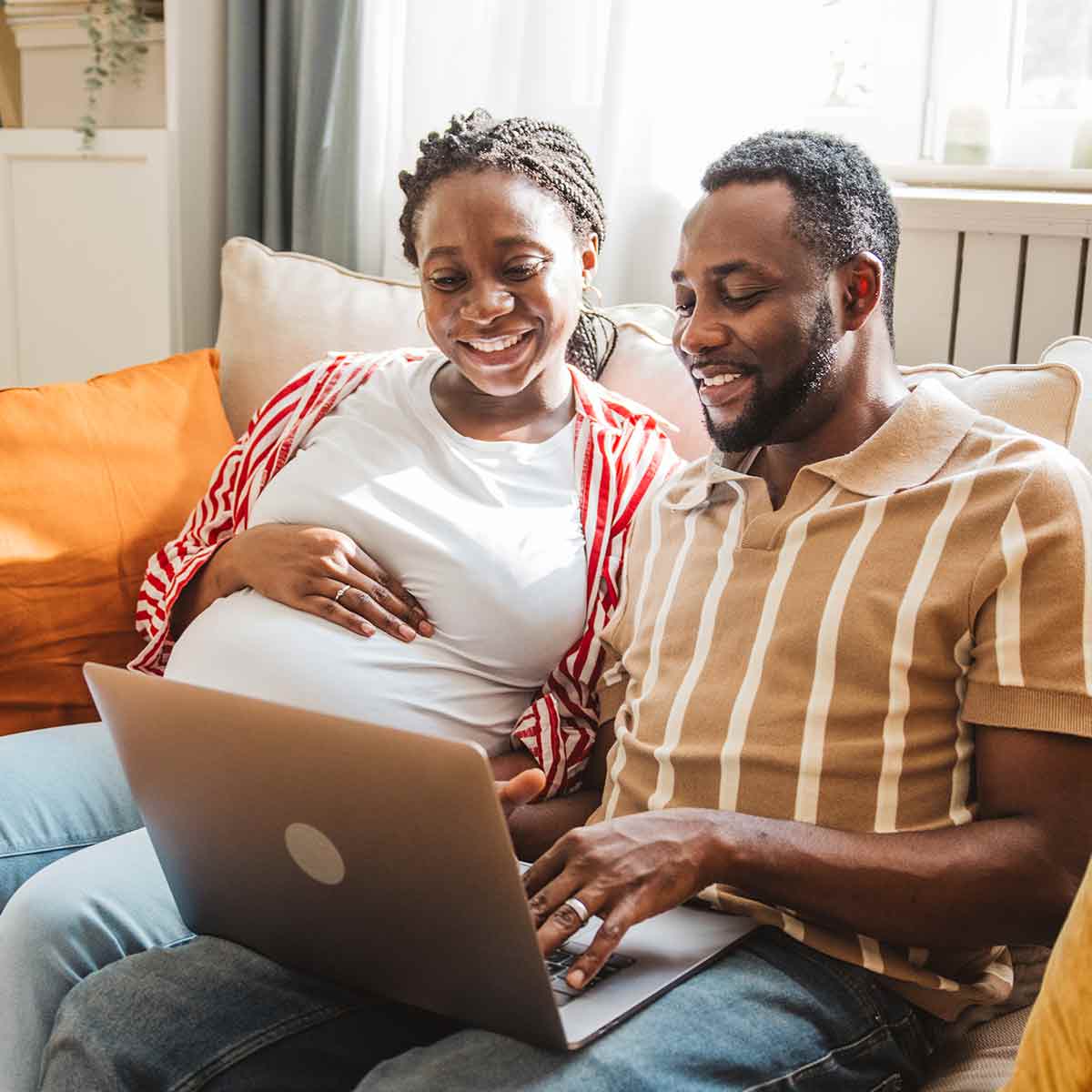 Expectant couple reviewing their finances together on a laptop at home