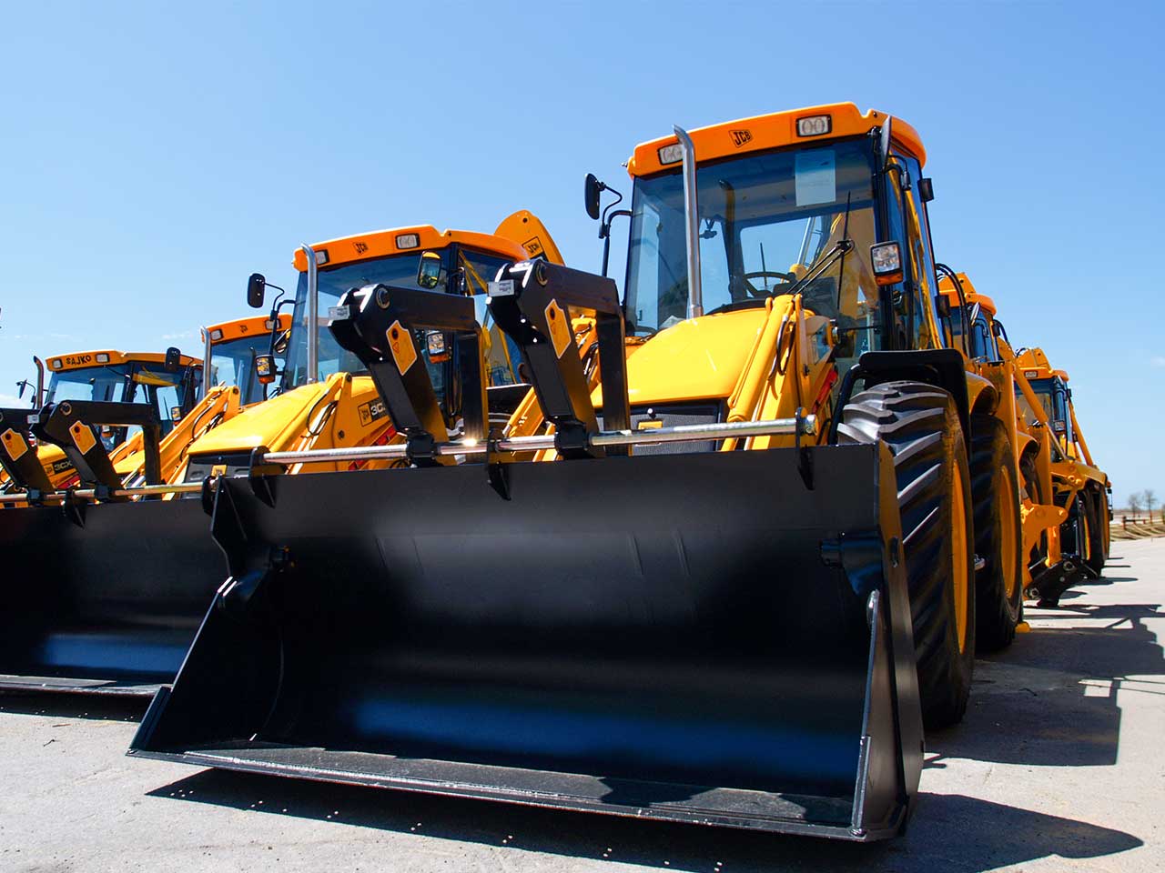 Heavy construction equipment lined up in an equipment yard
