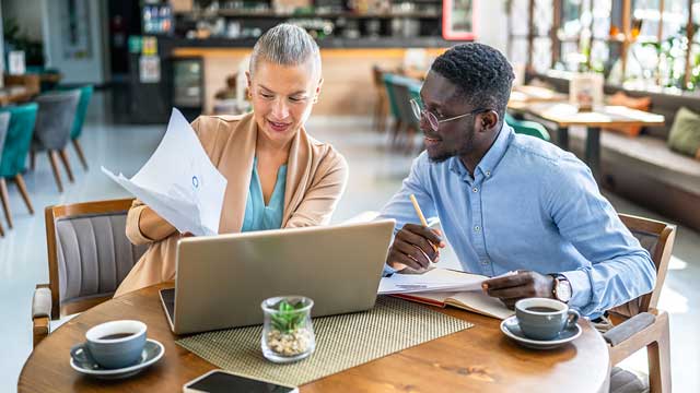 Banker and client in a coffee shop, reviewing financing options during early acquisition planning
